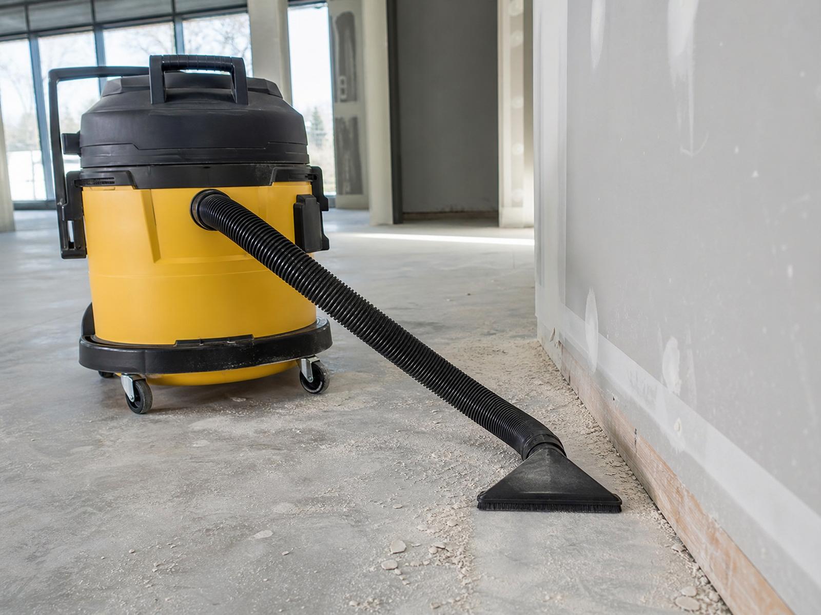 Heavy-duty HEPA shop vacuum removing drywall dust from a new commercial construction interior